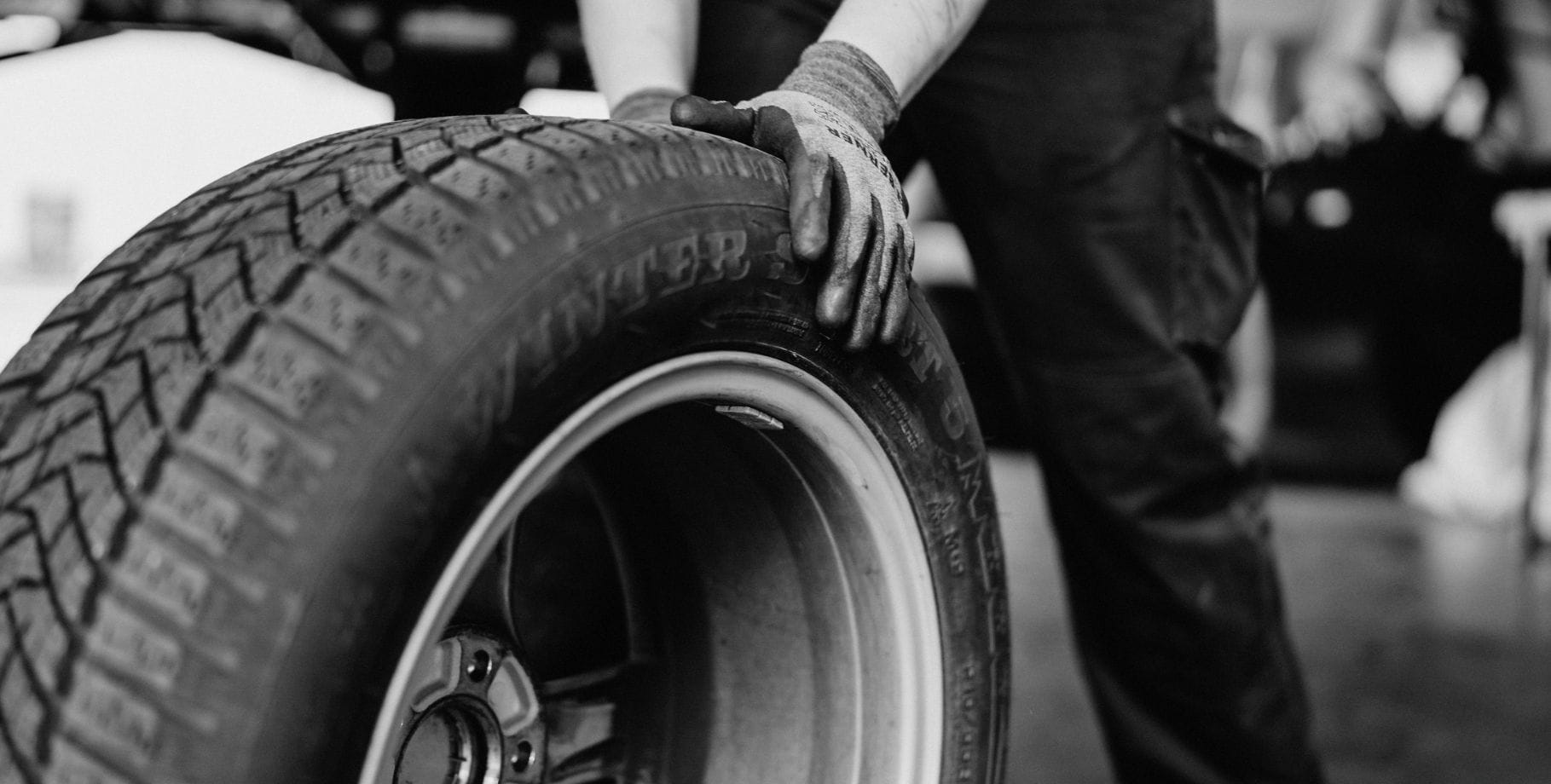 Mechaniker beim Reifenwechsel an einem PKW in einer professionellen Werkstatt.