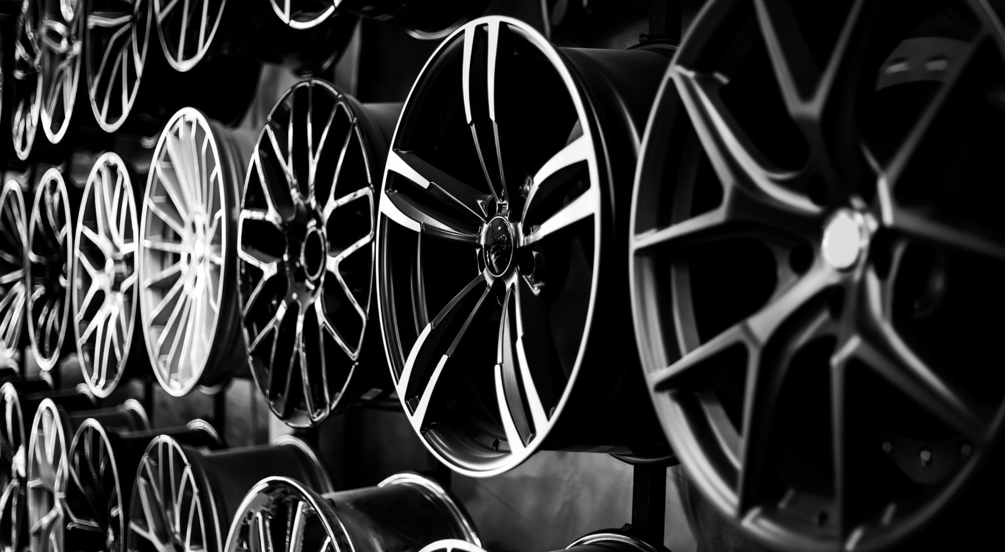 Alufelgen ordentlich nebeneinander aufgereiht in einem Verkaufsregal.