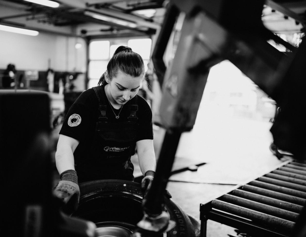 Jennifer Darmann in Arbeitskleidung in der Werkstatt, freundlich lächelnd.
