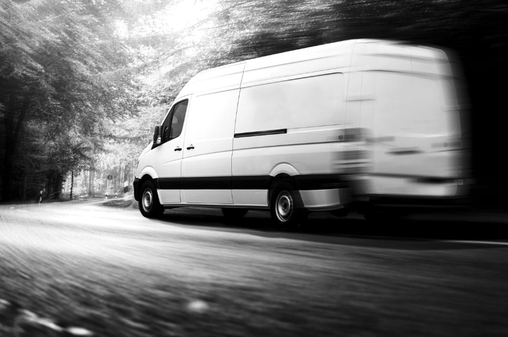Ein LKW mit Auflieger fährt auf einer Straße, fotografiert in Bewegung mit leichtem Unschärfeeffekt.